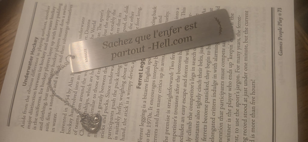 Engraved stainless steel bookmark with charm on an open book