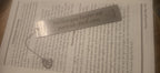 Engraved stainless steel bookmark with charm on an open book
