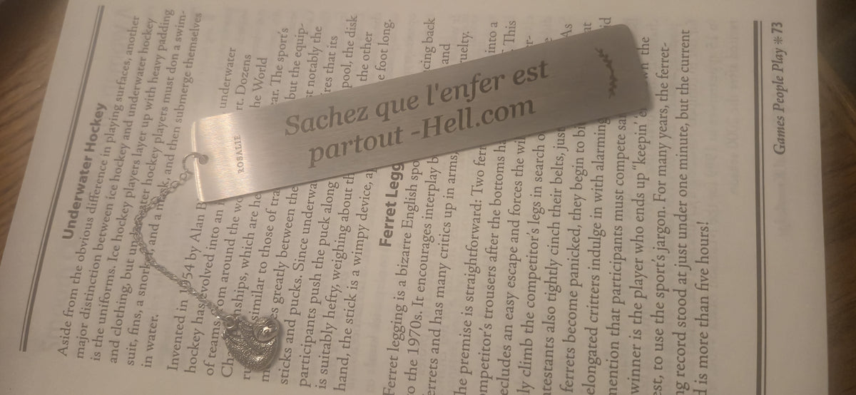 Engraved stainless steel bookmark with charm on an open book